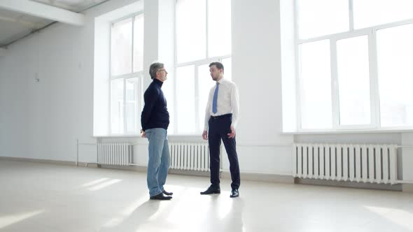 Businessman Discusses with Realtor Terms of Renting an Office Space Front View alt