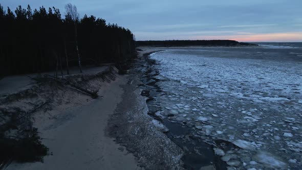 Scenic Sunset Ice Drifting with Fallen Trees During Windy Weather with Waves at Aerial View alt