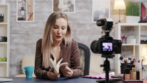 Attractive Beauty Blogger Reviewing a Book for Her Audience alt
