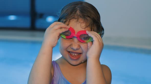Portrait of Cute Little Girl Putting Swim Glasses on Her Eyes in Indoor Pool
