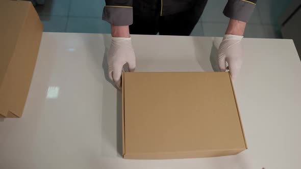 Top View of Male Hands in Gloves Passing Disposable Cardboard Box for Delivery Person in Restaurant alt