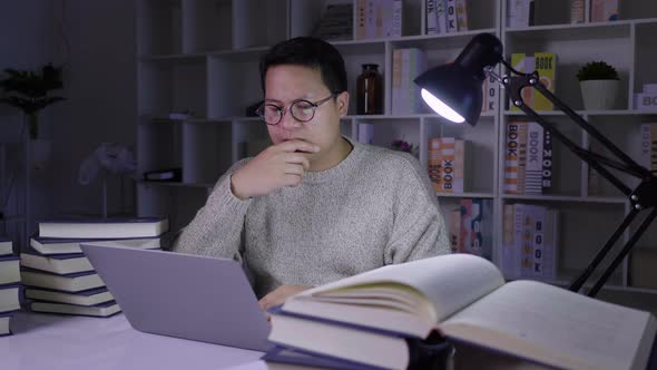 Serious man working on laptop at night, determining information with stressed face on working table alt