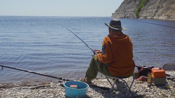 A Fisherman with a Hat Caught a Small Fish in a Bay on the River. Fishing on the Volga.
