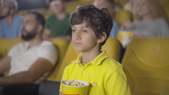 Cute Middle Eastern Boy Showing Hush Gesture in Cinema. Portrait of Happy Little Kid Enjoying Film alt