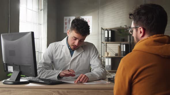 Qualified Doctor in the 30s Explains the Diagnosis to a Young Man in the Hospital alt