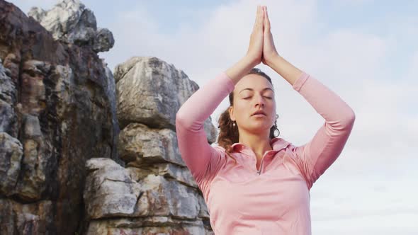 Caucasian woman practicing yoga meditation outdoors in rural mountainside setting alt