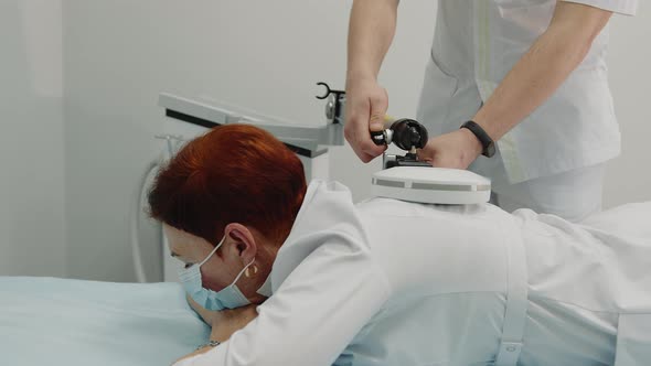 the Doctor Performs a Shock Wave Therapy Procedure to Treat the Patient's Back alt