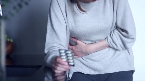 Woman Holding Medicine Against Stomachache alt