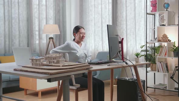 Asian Woman Engineer With The House Model Having A Backache While Working On A Desktop At Home alt