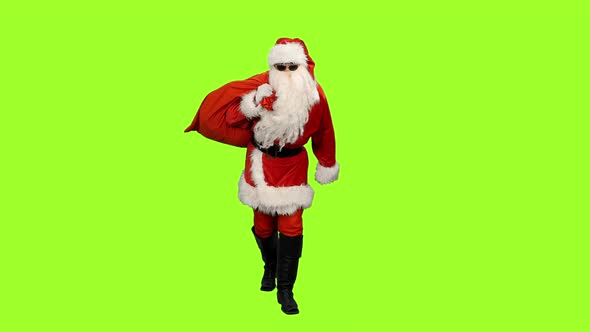 Santa Claus in Sunglasses Carrying Christmas Gifts in Sack on Green Background