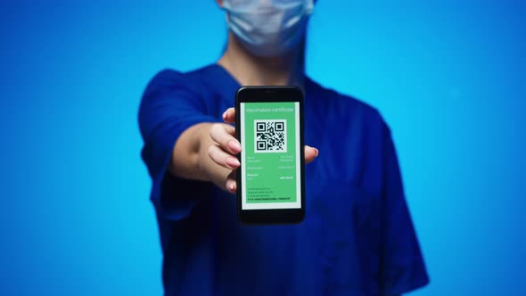 Woman Surgeon in Medical Uniform Showing Vaccination Passport with Qr Code on Phone International alt