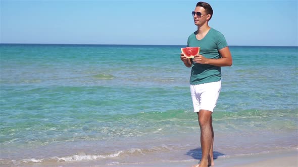 Happy Man Having Fun on the Beach and Eating Watermelon