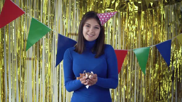Atmosphere of a Holiday Party at Home in the Room and a Caucasian Girl Standing in a Festive Hat alt