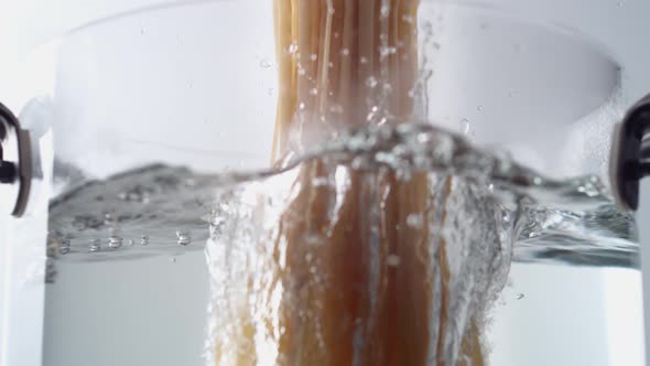 Camera follows cooking linguine noodles in boiling water. Slow Motion. alt