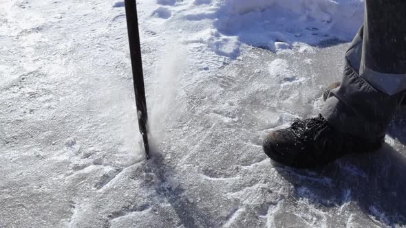 The Worker Hits the Ice with a Crowbar and Splashes and Snow Crystals Fly