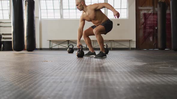 Fit caucasian man working out with kettle bell at the gym alt