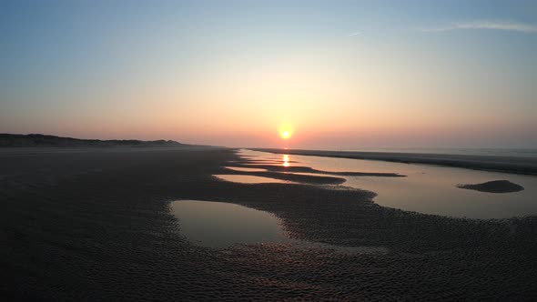 Aerial, tracking, drone shot over calm sea and patterns on the beach, on Langeoog island alt