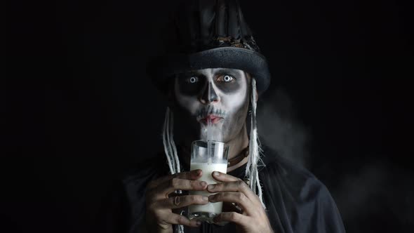 Creepy Man with Skeleton Makeup in Top-hat. Guy Looking at Camera, Drinks Milk From a Glass alt