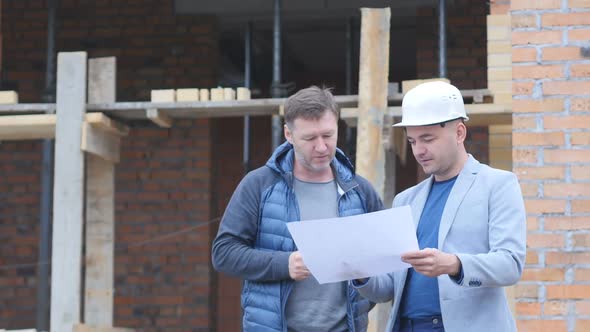 Construction Worker and Engineer Talking at Construction Site Site