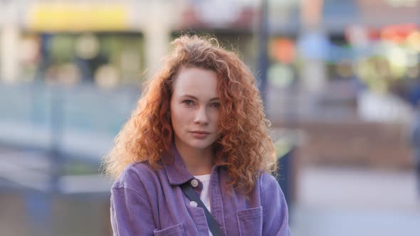 Redheaded woman standing in the city, looking at camera