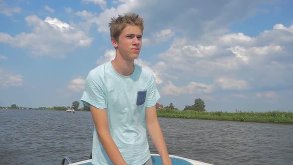 Young man is sailing a electric sloop in The Netherlands Friesland in the summer in Slowmotion. alt