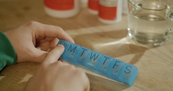 Man's Hands Taking Pills From Plastic Pill Organizer Box