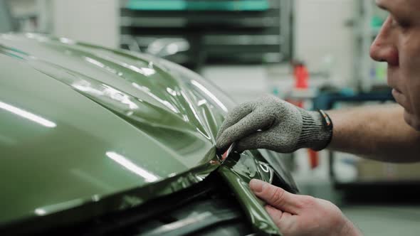 Mechanic Cutting Vinyl Car Wrap on a Car Hood Vinyl Wrapping Process