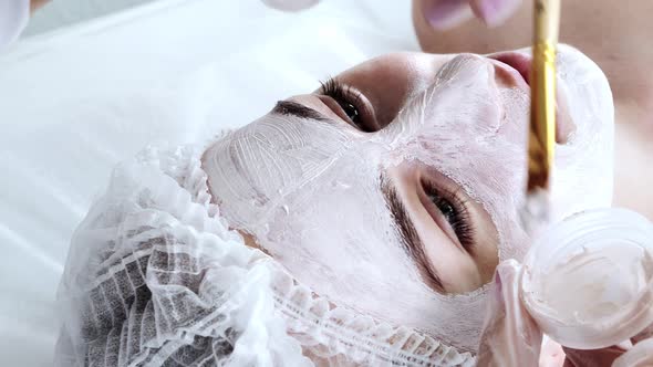 A beautician applies a mask to the skin of a woman's face for therapeutic purposes. Rejuvenation alt