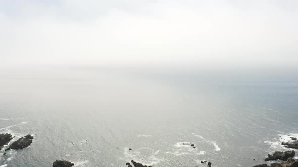 Aerial tilt down over the ocean to the rocky coast of Sea Ranch, California alt
