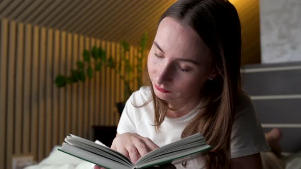 Woman Reads a Book at Home on Her Bed in the Evening alt