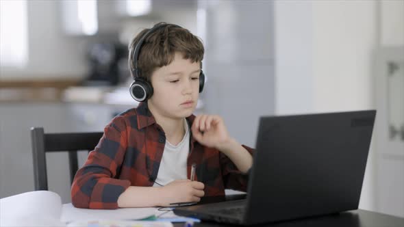 Overstressed boy listening to online class on laptop