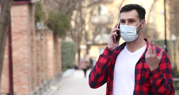 Young man wearing mask talks on the phone.