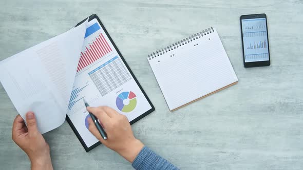 Trader Hand Checking Profits And Drawing Data In Note Pad. alt