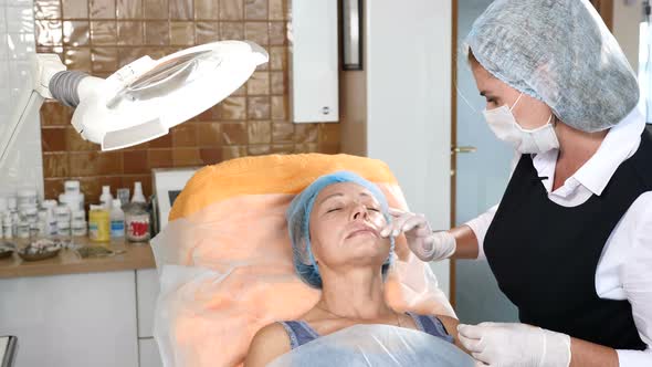 Beautician in Healthcare Clinic Applying Anesthesia Before Facial Procedure alt