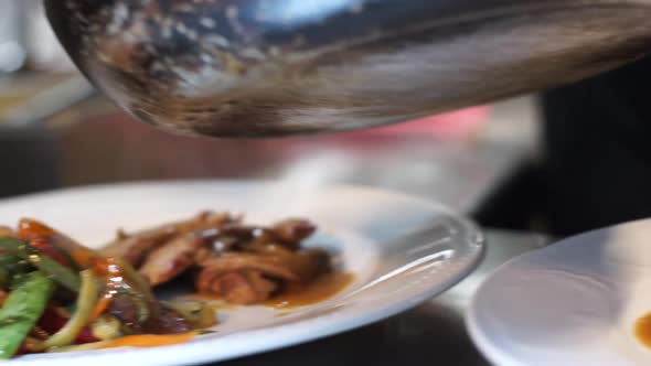 Highlight of a cook in an italian restaurant located in Athens, Greece serving two dishes of pork an alt