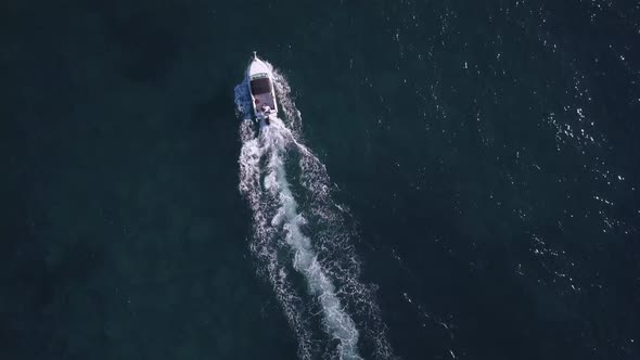 Overhead top down birds view of an adult in boat on the blue Pacific ocean water alt