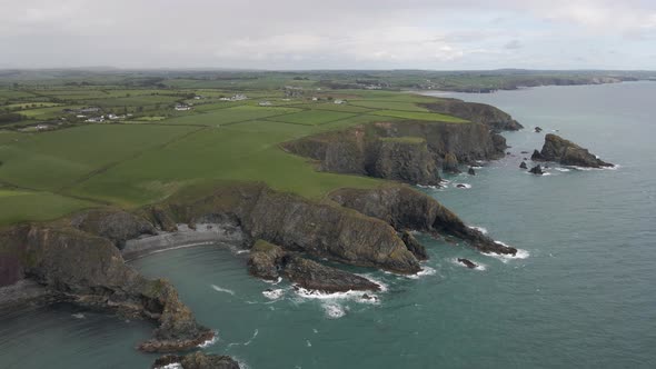 Drone shot of a coastline in rural Ireland with many sea cliffs, beaches and rock formations on a cl alt