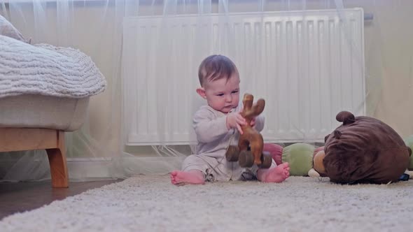 A happy child is playing with a wooden toy on the carpet in the nursery. Toddler baby boy is playing