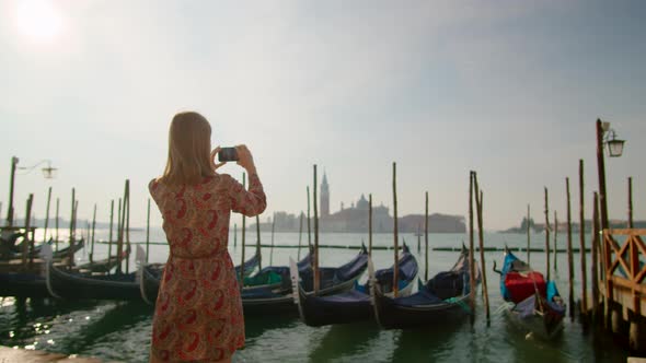 Pretty Lady Takes Photos By Phone with Gondolas in Venice Grand Canal Italy
