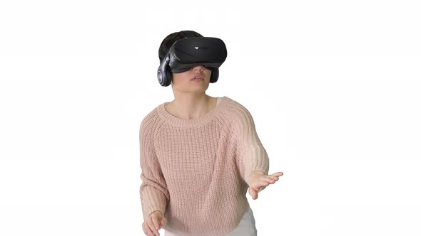 Cute Young Woman Walking and Using Interactive VR Headset on White Background. alt