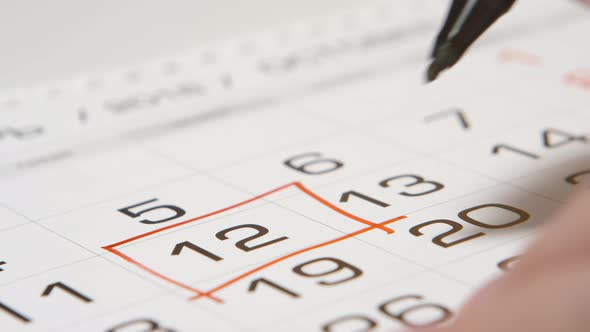 Signing a day on a calendar by red pen (square)