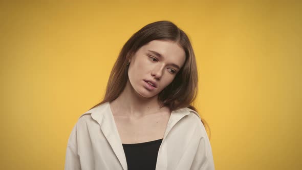 Young Adult Caucasian Woman is Unhappy on a Bright Yellow Background alt