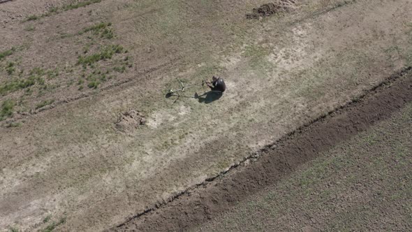 Drone View of Man Walking on Agricultural Field After Adjusting Lawn Mower alt