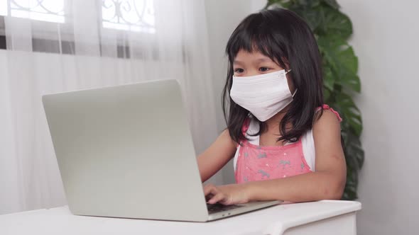 Funny Asian child learning class study online with a video calls from a notebook with a teacher alt