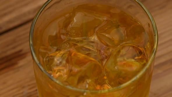 Ice cubes fall in glass of whiskey on bar counter alt