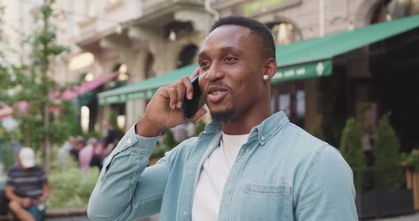 Man Enjoying His Positive Mobile Conversation Near Beautiful Street Cafe at Daytime in Summer alt