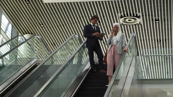 Young business people on an escalator in a modern building alt