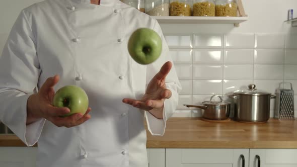Chief-Cooker Juggles A Green Apples In A Kitchen