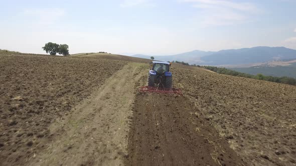 Farmer on tractor plowing a field in Umbria, Italy