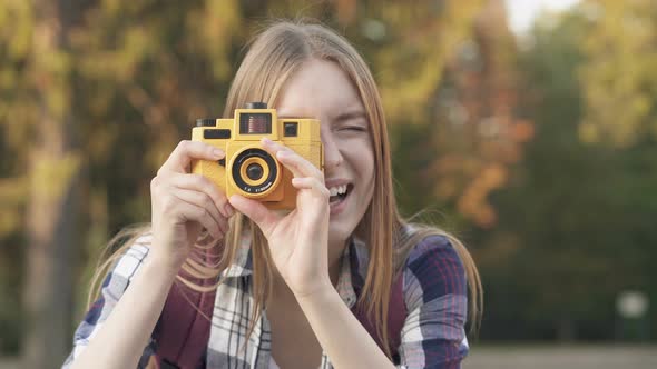 Happy, Smiling Young Woman Taking Pictures on The Vintage Camera